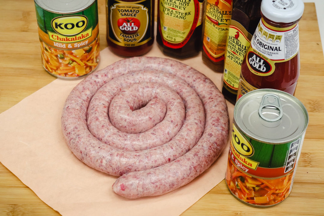 boerewors sausage rings on a butchers block with spices on the side