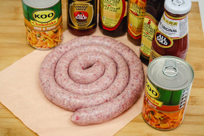 boerewors sausage rings on a butchers block with spices on the side