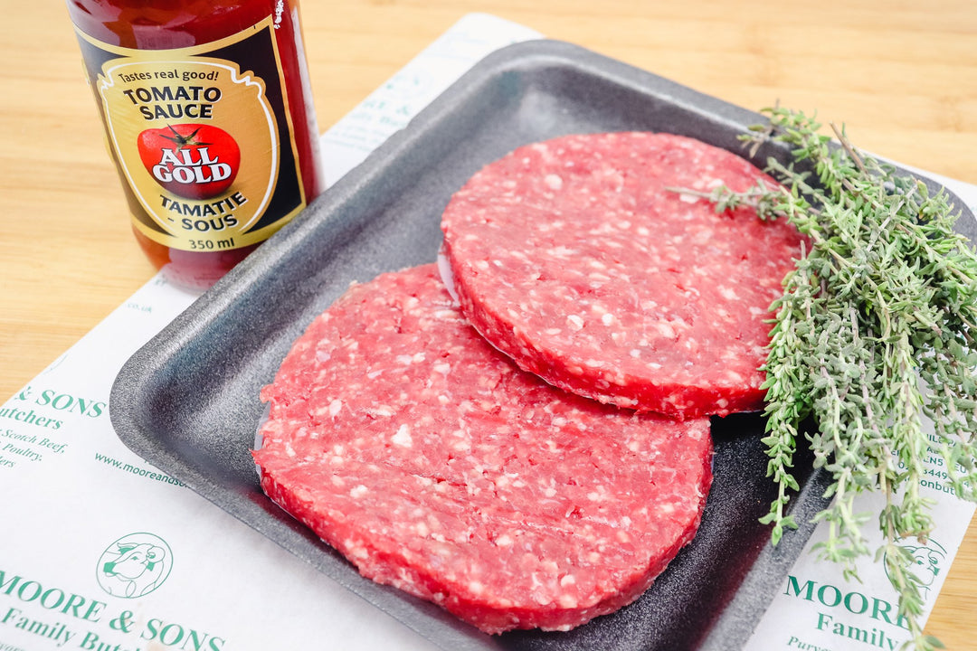 two burguers on a tray with herbs and tomato sauces on the side