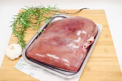 calves liver on a butchers block with rosemary and garlic on the side