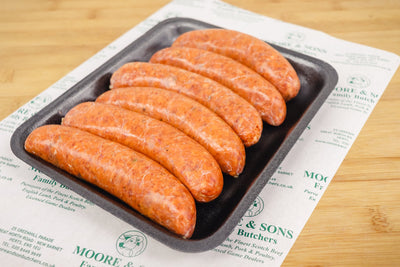 Six chorizo sausages on a black tray o top of a butchers block
