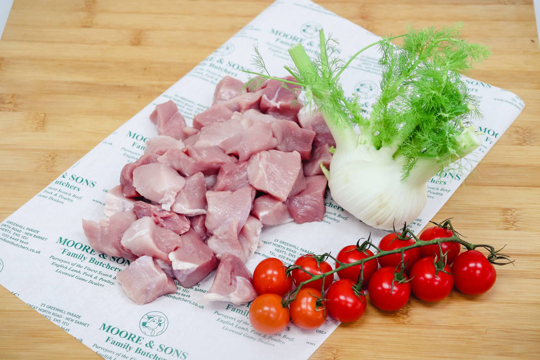 diced pork on a butchers block with onion and tomatoes on the side