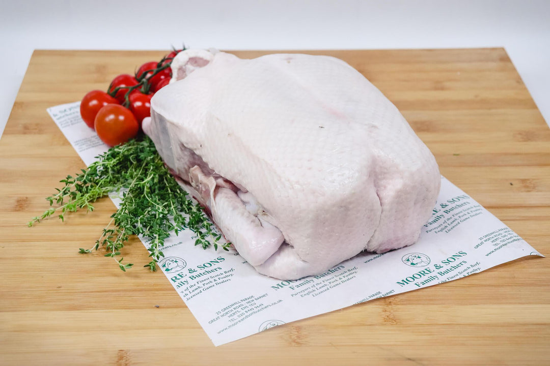 gressingham duck on a butchers block with tomatoes and herbs on the side