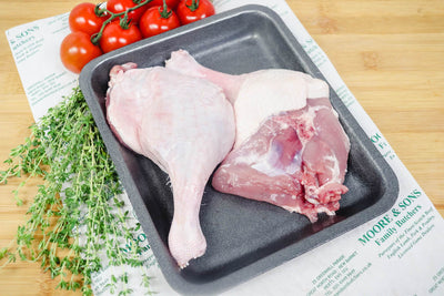 Barbary duck legs on a tray with herbs and tomatoes on the side