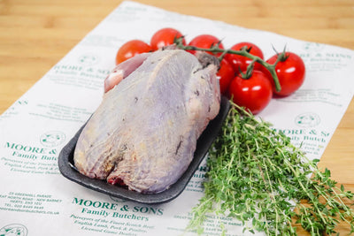 grouse on a butchers block with tomatoes and herbs ont he side