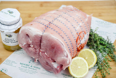 leg boneless rolled on a butchers block, with two lemons, herbs and bramley apple sauce