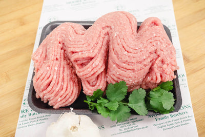 minced pork on a butchers block with herbs and onion on the side