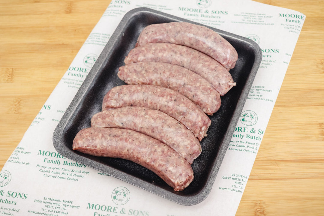 six moroccan sausages on a black tray on top of a butchers block