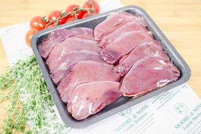pigeon breasts on a tray with herbs and tomatoes on the side