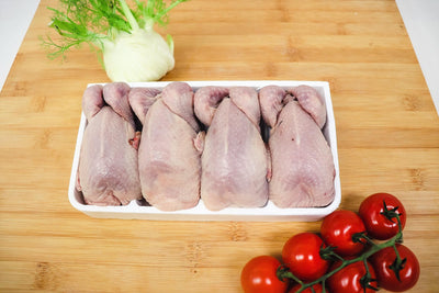 four quails on a butchers block with tomatoes and green onion on the side
