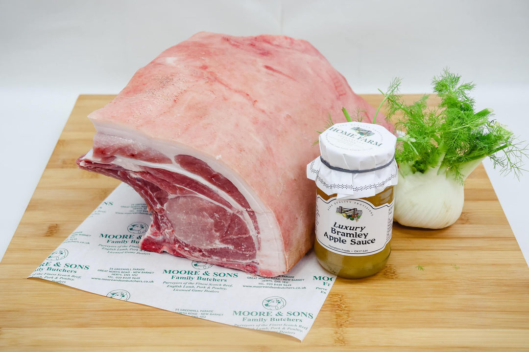 pork shoulder on a butchers block with green onion and bramley apple sauce