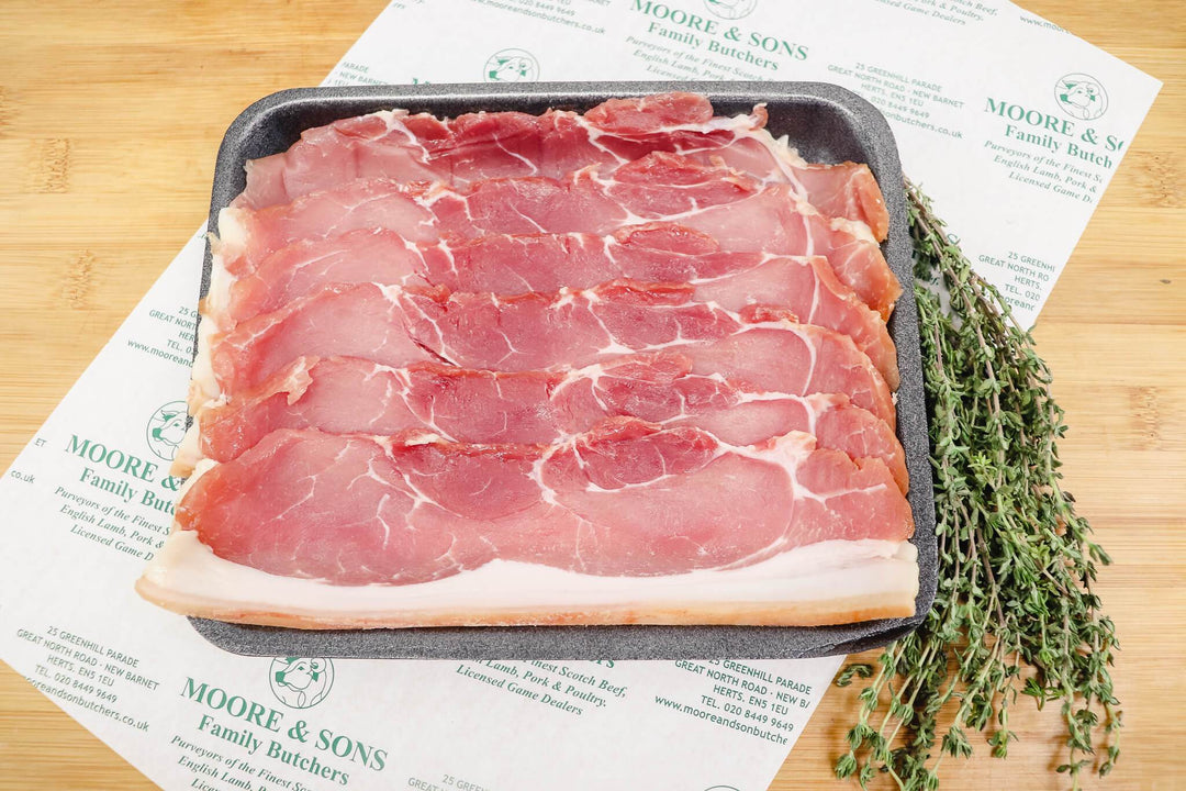 slices of smoked back bacon on a tray, with herbs on the side