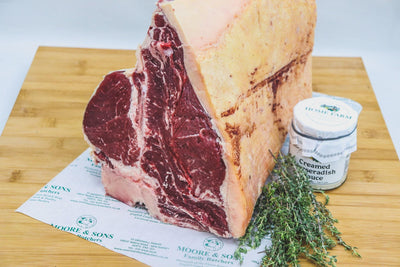 t-bone on a butcher block with herbs and creamed horseradish sauce on the side