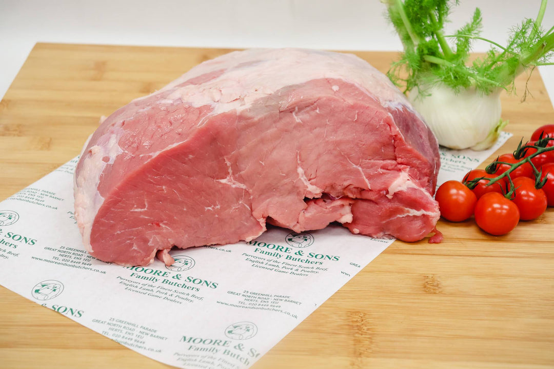 veal escalope on a butchers block with onion and tomatoes on the side