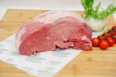 veal escalope on a butchers block with onion and tomatoes on the side