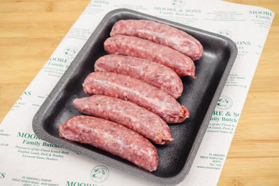 6 venison and red wine sausages on a black tray on top of a butchers block