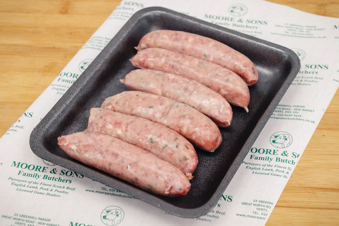 six wild board sausages on a black tray on top of a butchers block